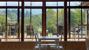 A wooden deck with a table and chairs, large windows with a view of trees and buildings. - MIZUKAMISO (Mizukami)