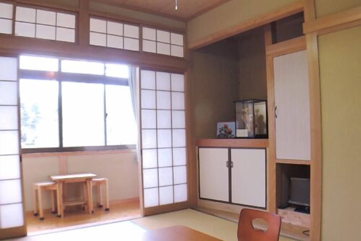 Ein traditioneller japanischer Raum mit Tatami-Böden, einem niedrigen Tisch, einem Stuhl und Schiebetüren.