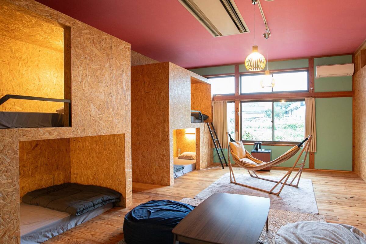 Ein Zimmer mit einer Hängematte, einem Bett, einem Schreibtisch und einem Fenster mit Blick.