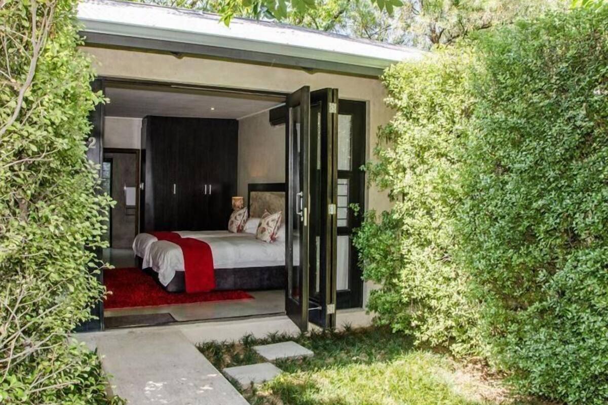 Une chambre moderne avec un grand lit, un dressing et une porte vitrée donnant sur un jardin.