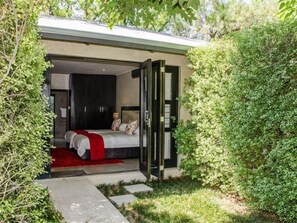 A bedroom with a bed, a red throw, and a view of a garden. - 9 On Kromellenboog Guesthouse (Metsimaholo)