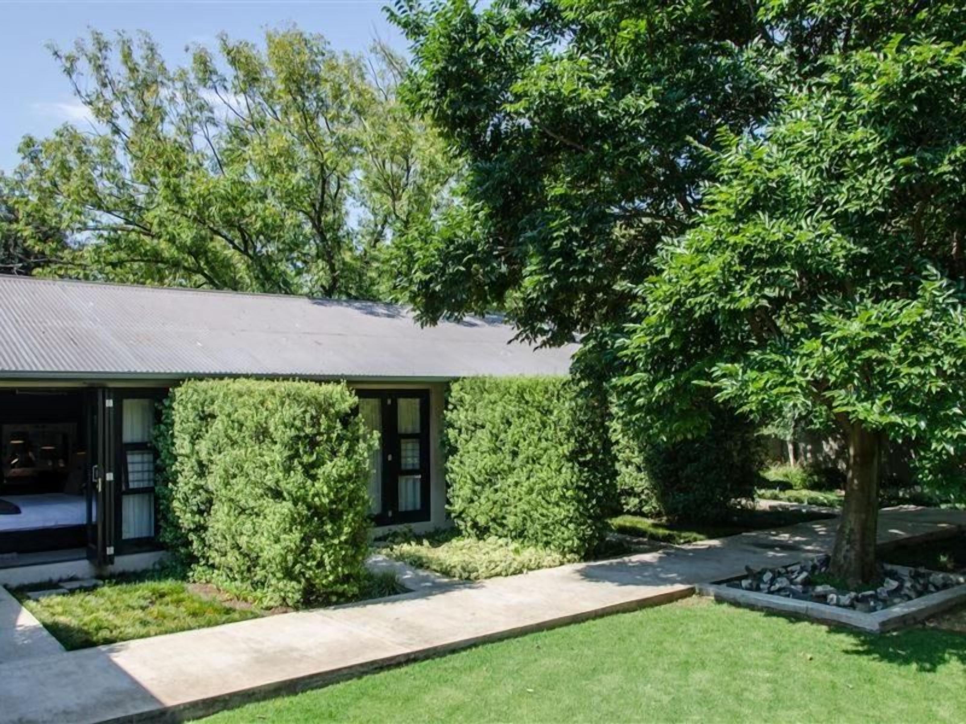 A modern house with a covered porch, a well-maintained lawn, and mature trees.