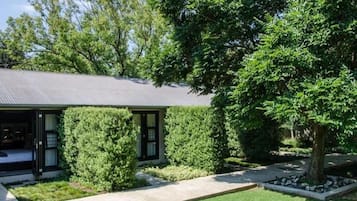 A modern house with a covered porch, a well-maintained lawn, and mature trees.