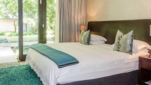 Une chambre avec un grand lit, une vue sur la verdure et une porte-fenêtre coulissante.