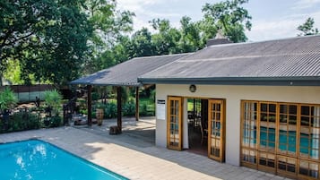 A poolside area with a pool, a covered seating area, and a building with large windows.
