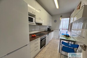 Compact kitchen with a stove, microwave, and coffee maker, perfect for preparing meals. A small dining table and chairs are also available.