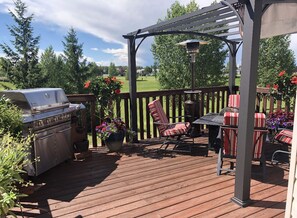 Relax and socialize on the deck, featuring a barbecue grill, comfortable seating, and a pergola for shade.