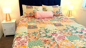 Ein Bett mit einer Blumensteck, einem dunklen Kopfteil und zwei Nachttischlampen.