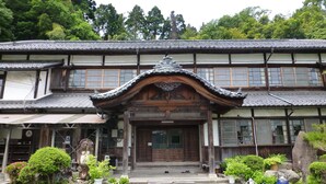 Un bâtiment japonais traditionnel, doté d’une entrée en bois, de nombreuses fenêtres et d’un toit recouvert de tuiles.