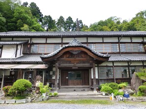 Un bâtiment japonais traditionnel, doté d’une entrée en bois, de nombreuses fenêtres et d’un toit recouvert de tuiles.
