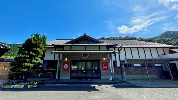 Een traditioneel Japans gebouw met pannendak, overdekte entree en een bord.