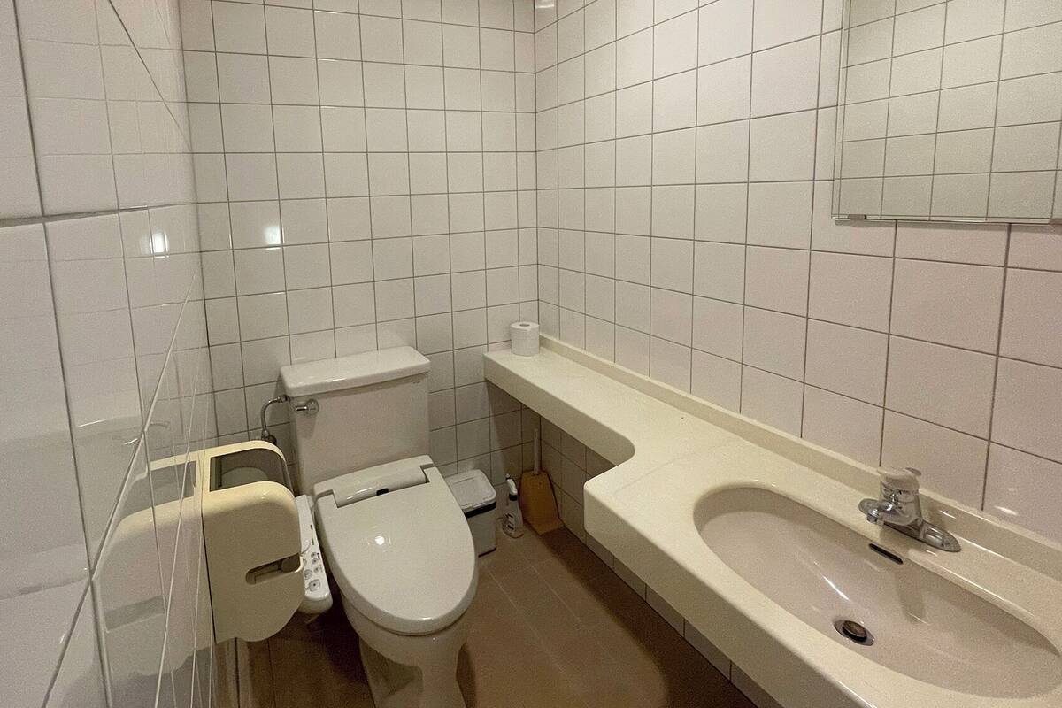 Une petite salle de bain propre, équipée de toilettes, d’un lavabo et d’un miroir au-dessus du lavabo.