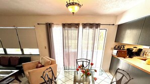 A dining area with a glass table, four chairs, and a vase with flowers. - Vacation guest pool home (Naples)