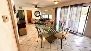 A dining area with a glass table, chairs, and a ceiling fan. - Vacation guest pool home (Naples)