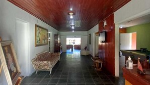 A spacious room with a wooden ceiling, a sofa, a painting, and a billiards table. - Pousada Cavalo de Pedra (Peruíbe)
