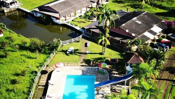 An aerial view of a resort with a swimming pool, a boat dock, and lush greenery. - Pousada Cavalo de Pedra (Peruíbe)