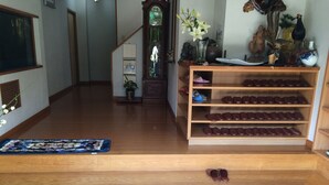 Un zapatero de madera con varios estantes, un banco de madera y un piso de baldosas.