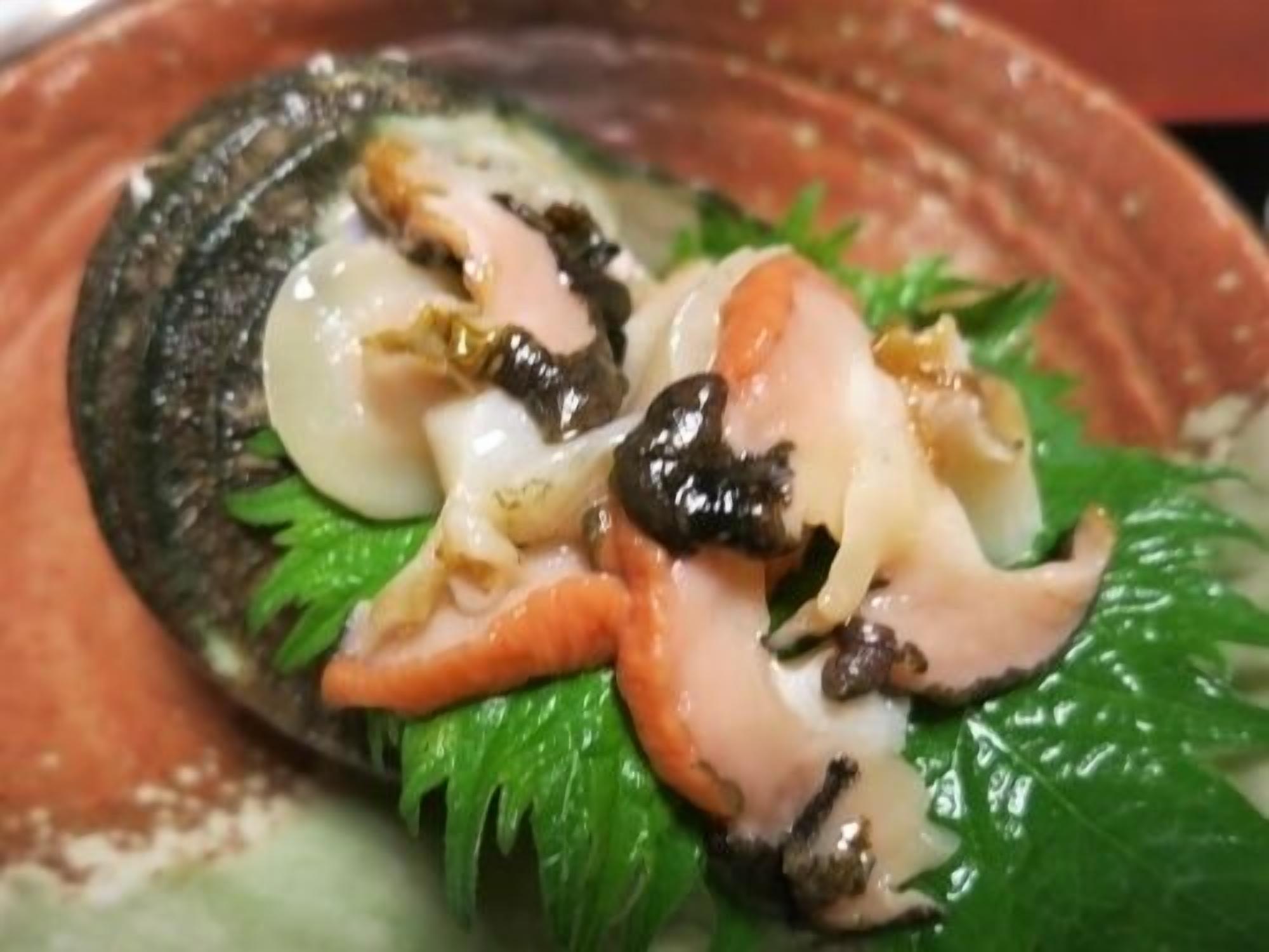 Un plato de mariscos, posiblemente cangrejo, adornado con hojas verdes y salsa.