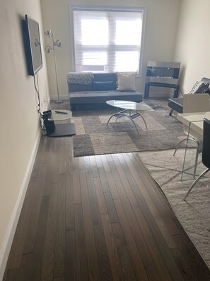 A living room with a sofa, coffee table, and a TV mounted on the wall. - Huge 2 bed/2bath Condo in beautiful Downtown Newark, NJ (Newark)