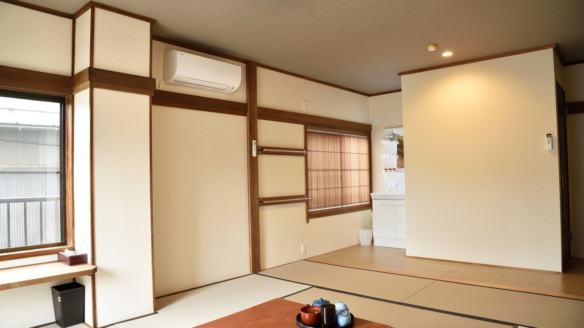 A traditional Japanese room with tatami flooring, a sliding door, a window with a view, and a kitchen area.