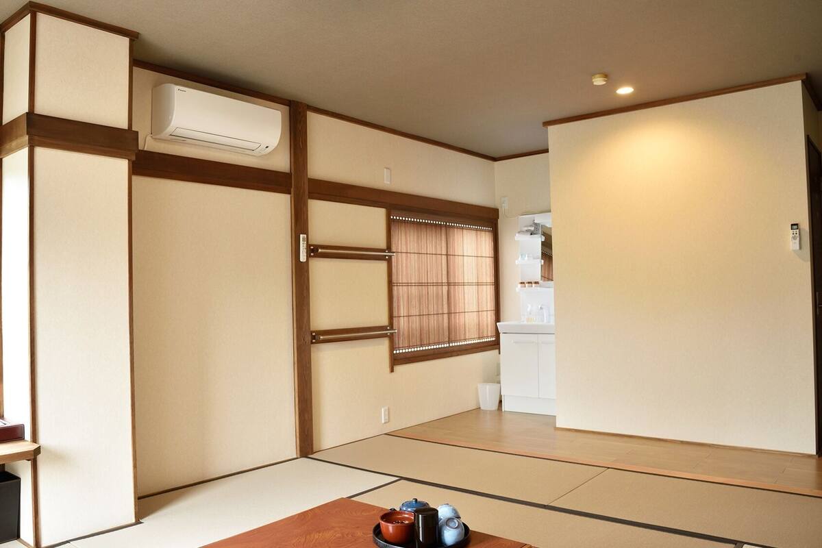 Una tradizionale stanza giapponese con pavimentazione in tatami, scorrevole, una finestra con vista e un angolo cottura.