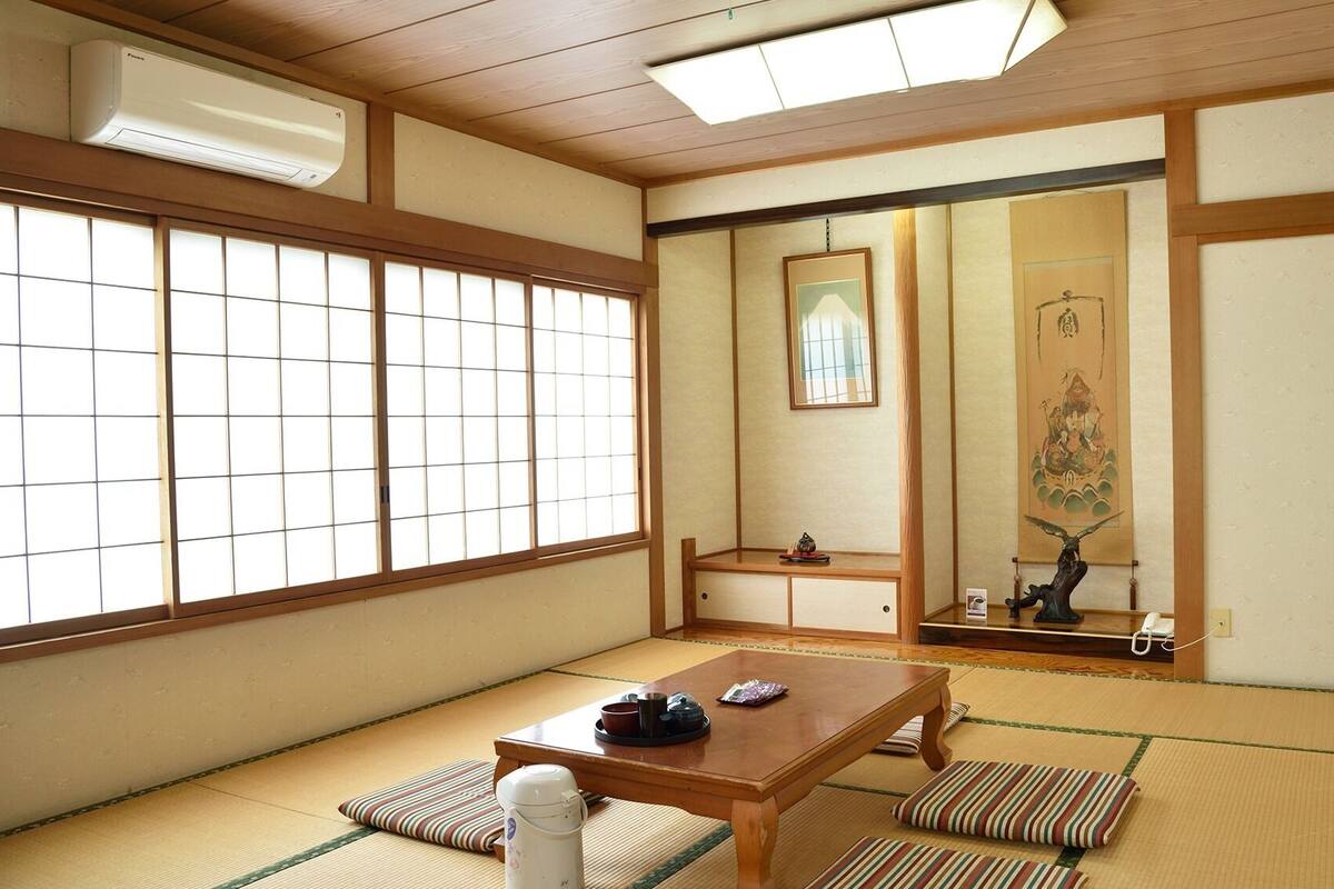 Una stanza tradizionale giapponese con pavimento in tatami, un tavolino di legno, una porta scorrevole e un paravento shoji.