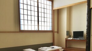 A traditional Japanese room with tatami flooring, a futon bed, a television on a wooden stand, and a shoji screen window. - Hotel Shimizuso (Sakura)