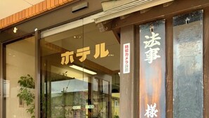 A hotel entrance with a red carpet, glass doors, and a potted plant. - Hotel Shimizuso (Sakura)