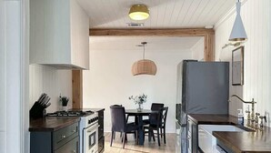 Et moderne køkken med en central ø, trægulv og et spiseområde med bord og stole.