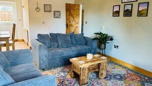 Un salon avec un canapé bleu, une table basse en bois et un tapis aux couleurs vives.