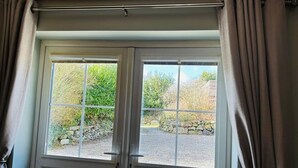 Une porte à deux battants donnant sur un jardin et un mur de pierres.
