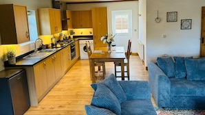 Une cuisine moderne avec des meubles en bois, un coin repas avec une table et des chaises, et un canapé bleu dans le salon.