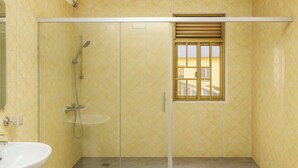 Un bagno con box doccia in vetro, un lavandino e una finestra.