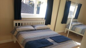 A single bed with a striped bedspread and pillows, a wooden headboard, and a window with curtains. - House - Sleeps 5 - Pets Ok - Parking - Garden (Bristol)