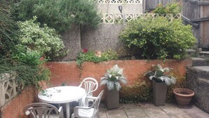A patio with a round table and four chairs, surrounded by potted plants and a decorative fence. - House - Sleeps 5 - Pets Ok - Parking - Garden (Bristol)