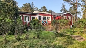 Ein rotes Gebäude mit einer Treppe, die zu einer Terrasse führt, umgeben von viel Grün.