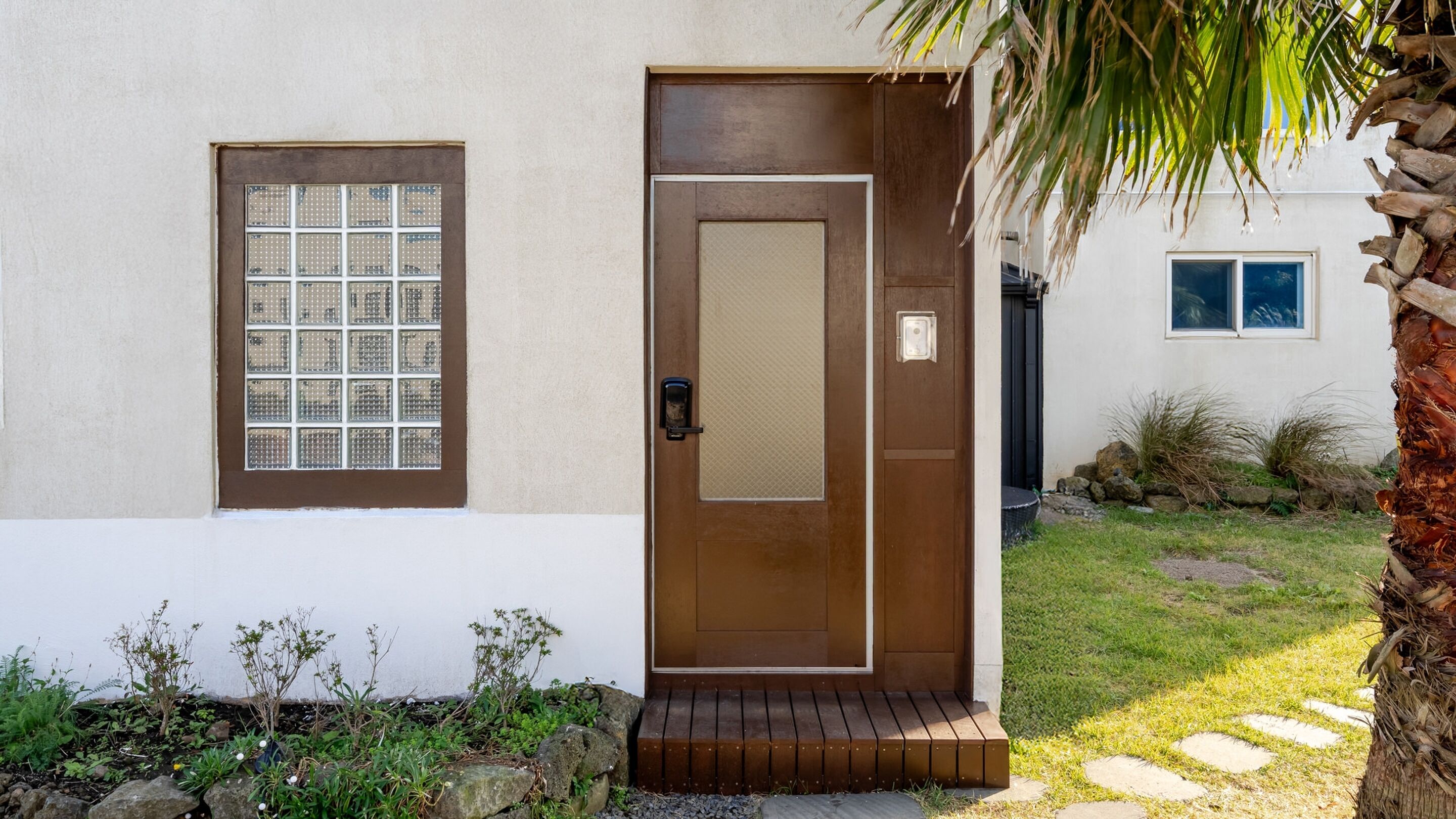Una casa moderna con puerta de madera, una ventana con diseño de cuadrícula y un porche pequeño.