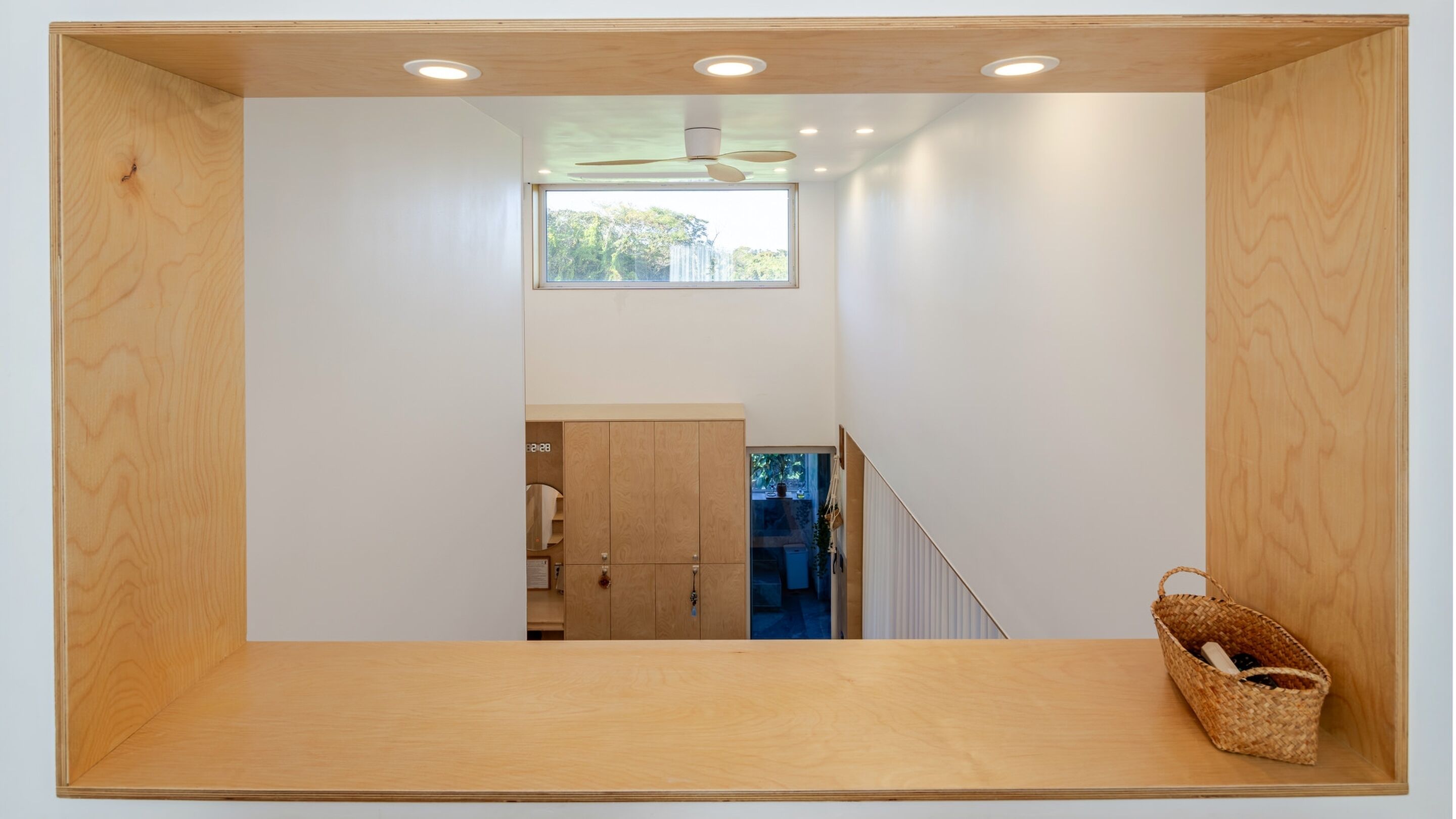 Una habitación moderna y minimalista con suelo de madera, ventilador de techo y un gran ventanal que proporciona luz natural.