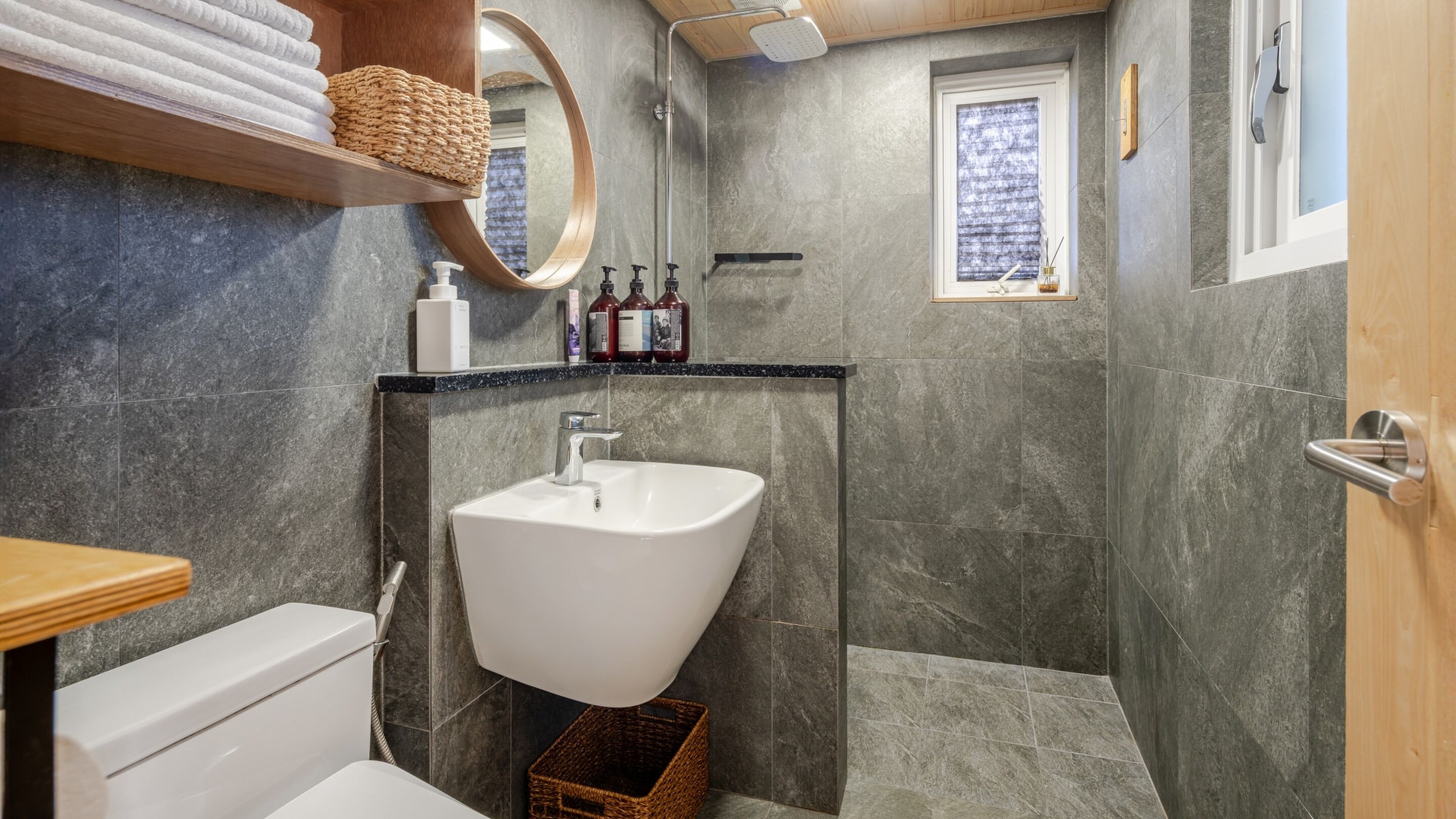 A modern bathroom with a freestanding sink, a toilet, and a shower area.