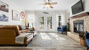 A living room with a brown leather sofa, a blue armchair, a fireplace, and a television mounted on the wall.