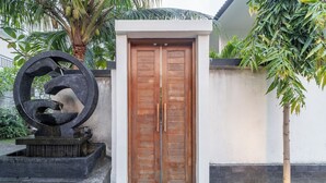 Une porte à deux battants en bois, avec un socle en béton et une sculpture décorative sur le côté gauche.