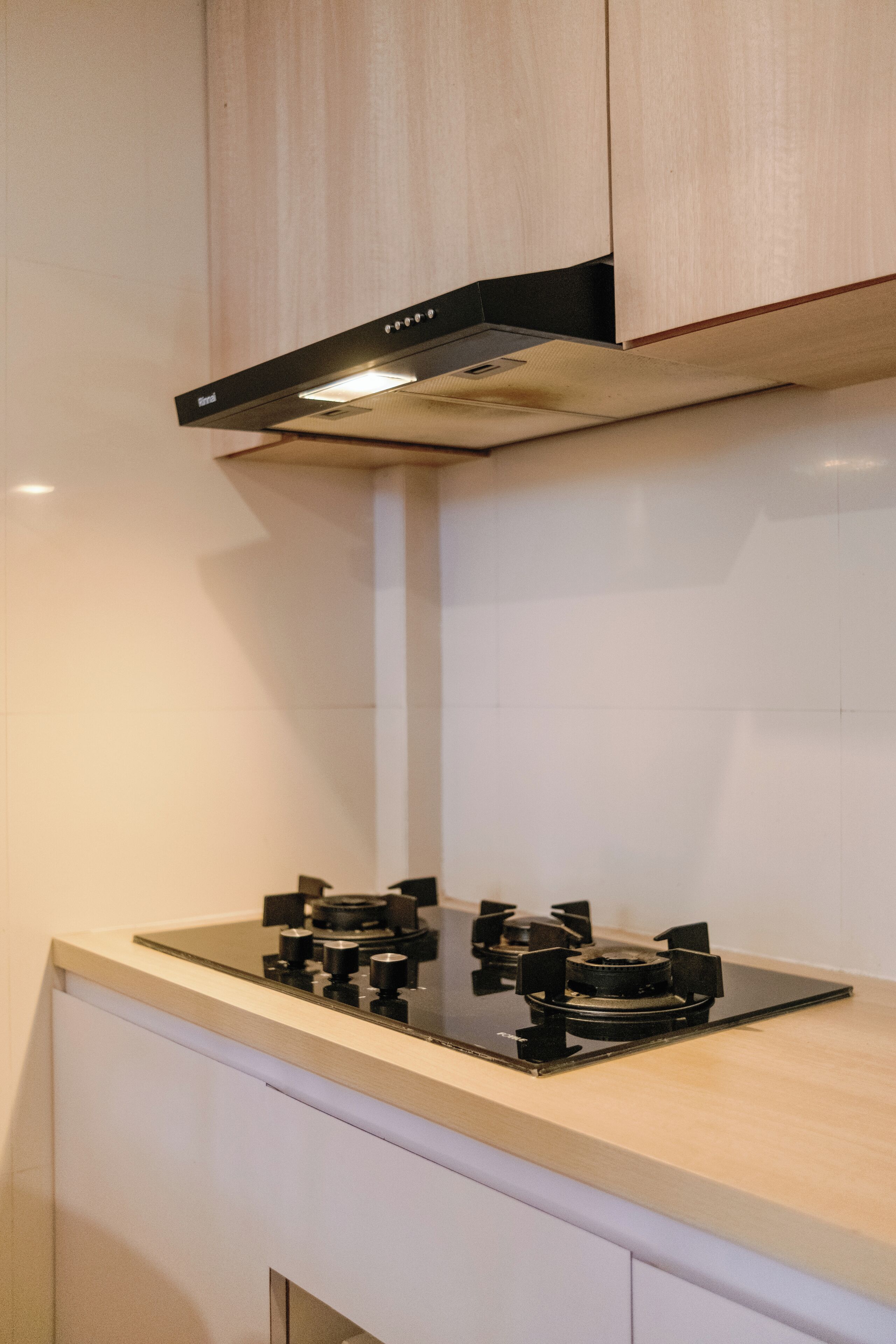 A kitchen with a gas stove, white cabinets, and a stainless steel range hood.