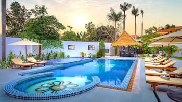 Una piscina al aire libre, sombrillas, sillones reclinables de piscina