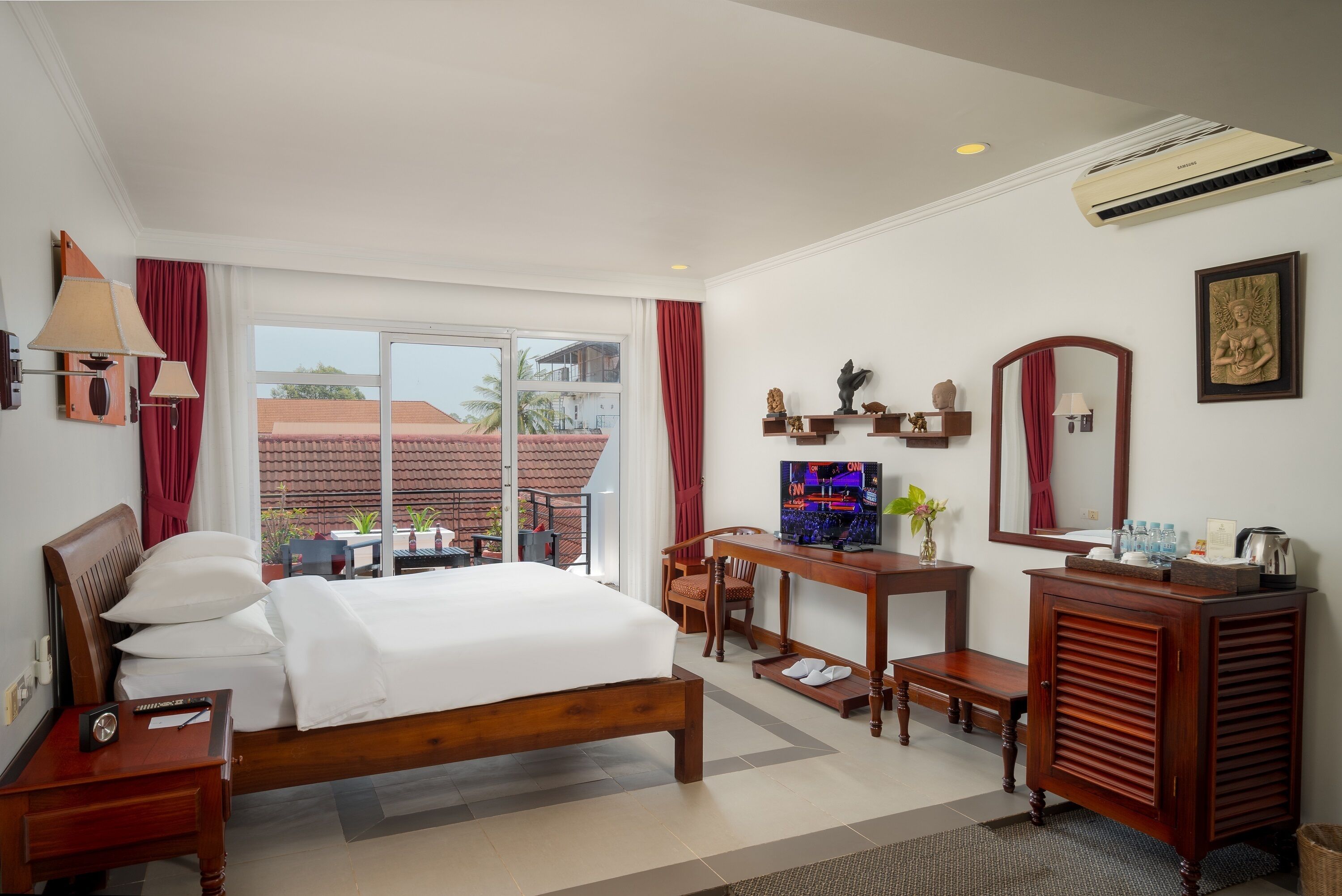 Une chambre d’hôtel équipée d’un lit, d’un bureau, d’une chaise, d’une coiffeuse et d’une grande fenêtre donnant sur des immeubles.
