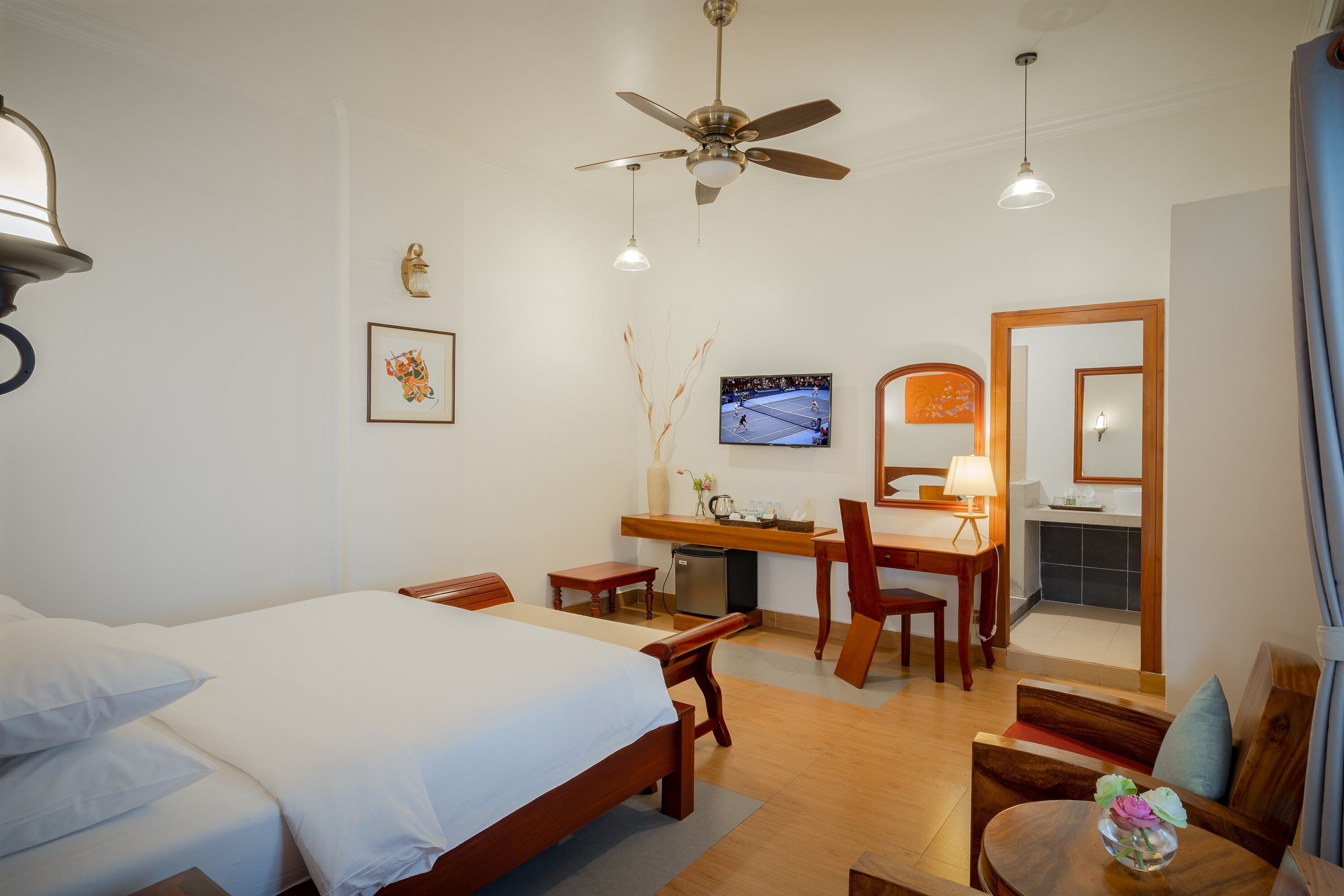 A hotel room with a bed, desk, chair, and a TV on the wall.