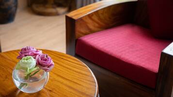 A wooden table with a vase of pink and green flowers.
