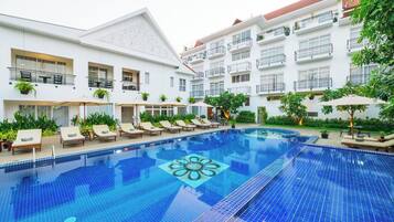 Una piscina al aire libre, sombrillas, sillones reclinables de piscina