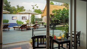 Un patio con sillones, sombrillas y una mesa de comedor con frutas y bebidas.