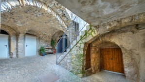 A stone-walled courtyard with a wooden door, a metal staircase, and a potted plant. - Casa Umberto near Lake Tenno, Tenno, Italy (Tenno)