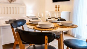 Mesa de comedor lista con cuencos blancos y copas de vino, rodeada de sillas negras con patas de madera.
